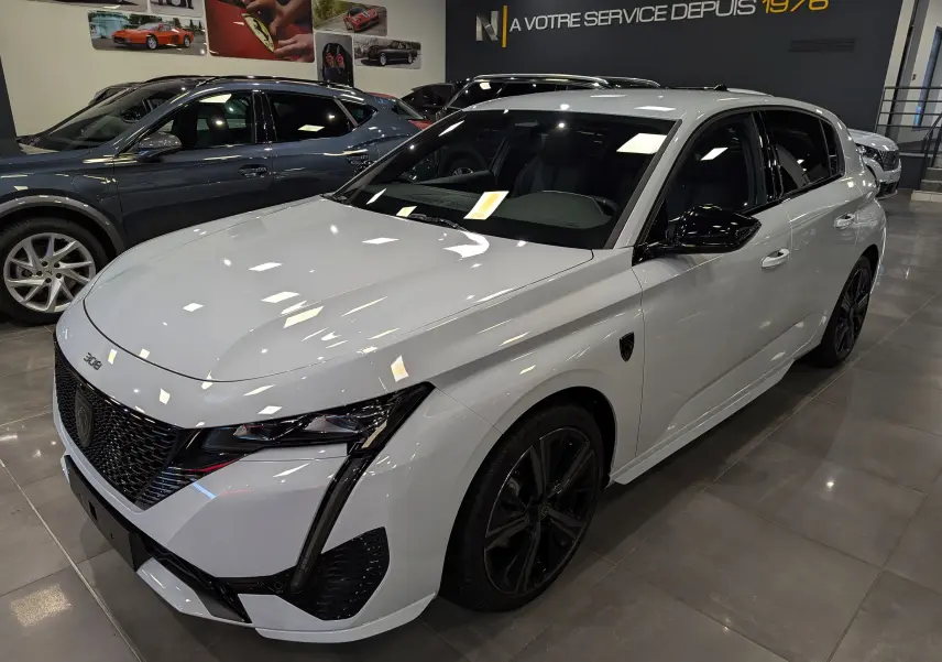 Peugeot 308 BlueHDi 130 GT blanc Okénite vue 3/4 avant droit dans un showroom moderne.