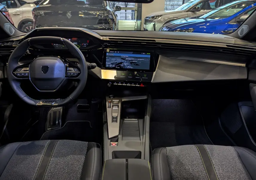 Intérieur moderne de la Peugeot 308 2024, vue frontale du tableau de bord avec écran tactile et volant compact noir.