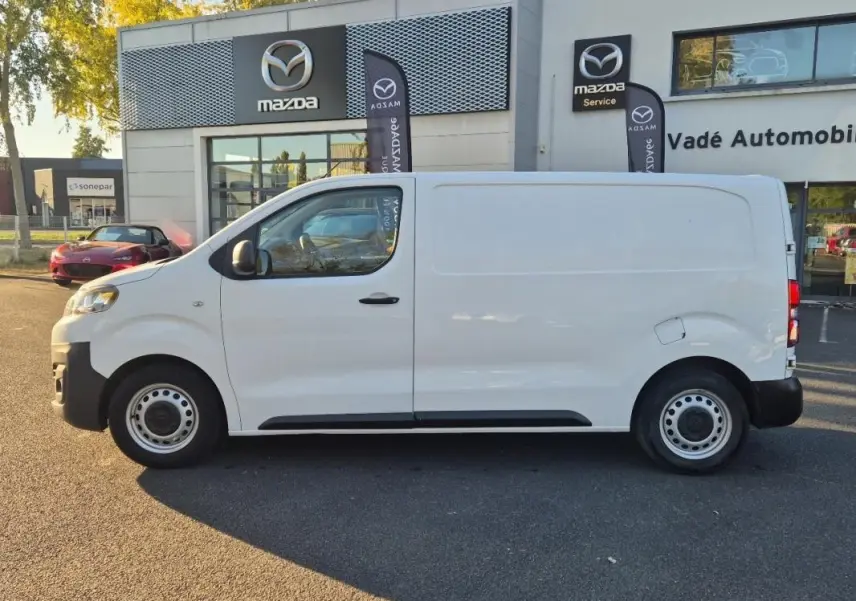 Vue de profil côté gauche d'un Citroën Jumpy blanc 2019, fourgon utilitaire devant un concessionnaire Mazda.
