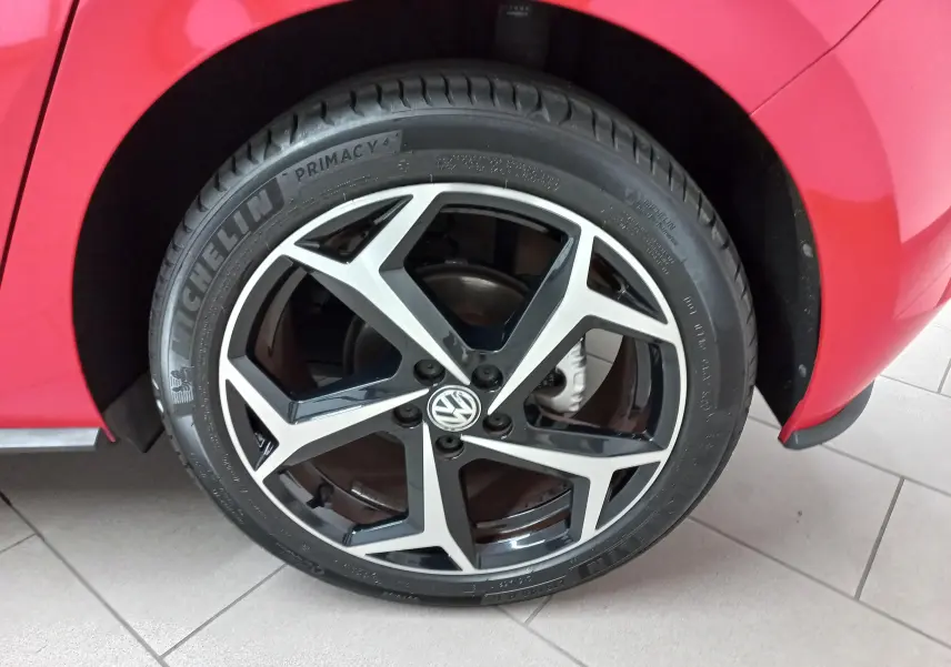Gros plan sur la roue avant gauche d'une Volkswagen Polo Rouge Flash avec jante alliage R-Line bicolore.