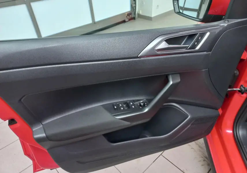 Vue intérieure de la porte côté gauche rouge flash d'une Volkswagen Polo 2019 avec commandes de vitres et verrouillage.