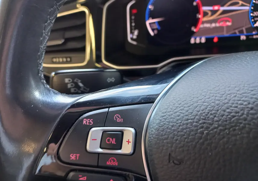 Gros plan sur les commandes au volant d'une Volkswagen Polo Rouge Flash avec affichage numérique actif en arrière-plan.