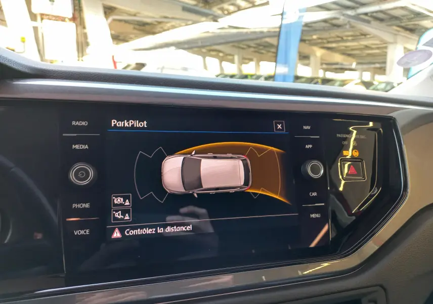 Affichage du système ParkPilot sur l'écran central de la Volkswagen Polo Rouge Flash, vue intérieure du tableau de bord.