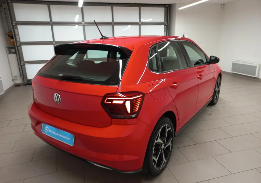 Volkswagen Polo Rouge Flash vue 3/4 arrière droit en intérieur, avec feux arrière LED et jantes R-Line noires.