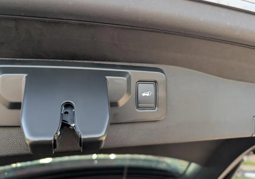 Détail du bouton d'ouverture électrique du hayon sur la partie intérieure du coffre du Renault Austral gris métallisé.