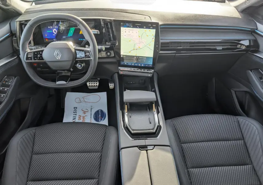 Vue intérieure avant du Renault Austral gris métallisé, avec tableau de bord digital et écran tactile vertical central.