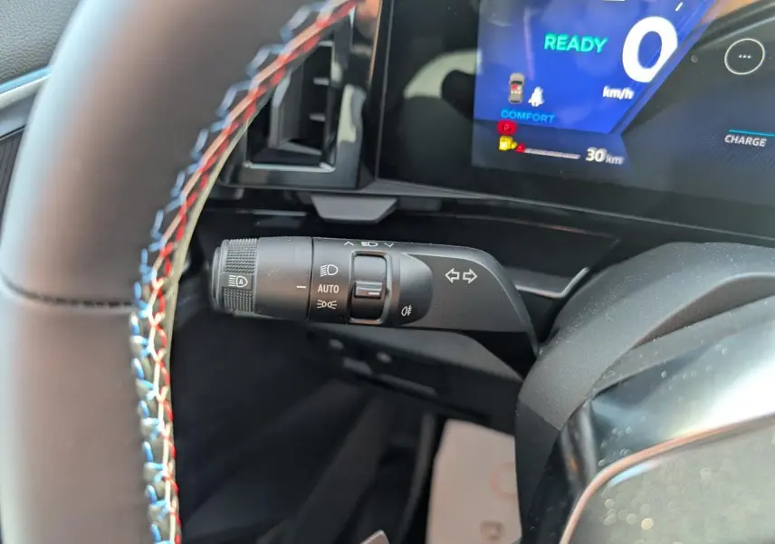 Gros plan sur la commande de clignotants à gauche du volant avec surpiqûres tricolores du Renault Austral gris métallisé.