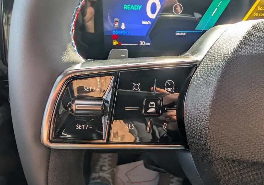 Gros plan sur les commandes au volant gauche du Renault Austral gris métallisé, affichage numérique en arrière-plan.