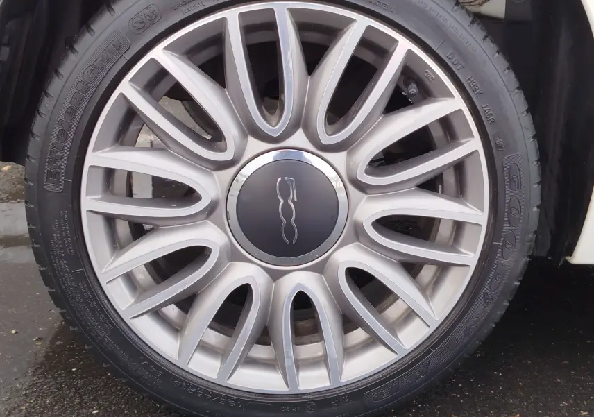 Gros plan sur la jante argentée en alliage de la Fiat 500 blanche, mettant en valeur le logo central distinctif.