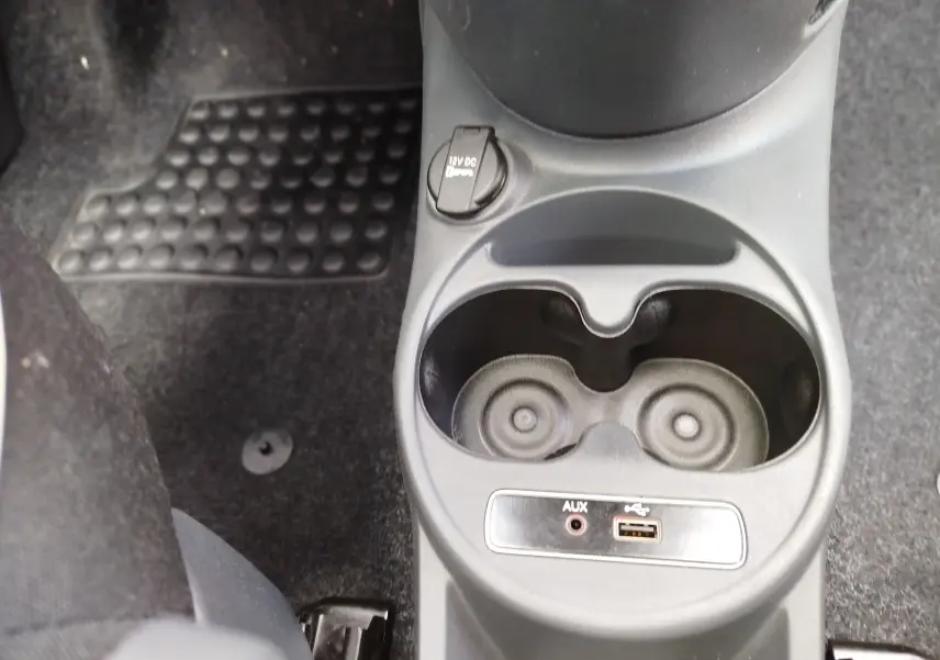 Gros plan sur la console centrale noire de la Fiat 500 Lounge 2017, avec porte-gobelets et prises AUX et USB.