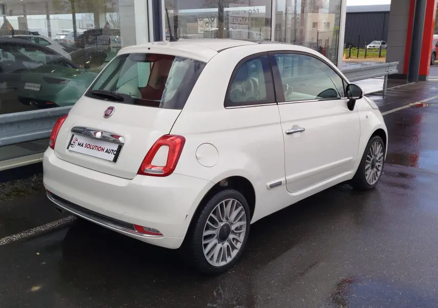 Vue 3/4 arrière droite d'une Fiat 500 Lounge blanche Bossa Nova avec jantes alliage et feux arrière LED.