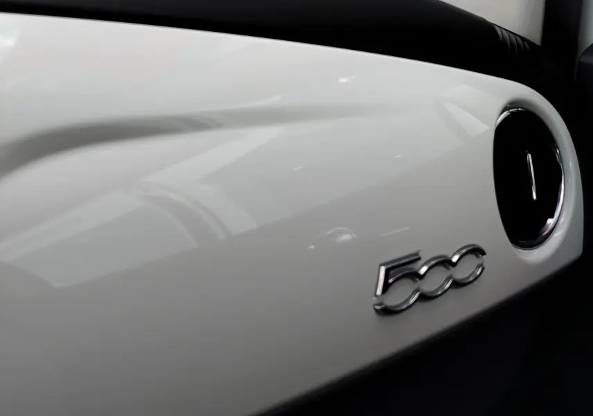 Gros plan sur le tableau de bord blanc Bossa Nova de la Fiat 500 2017 avec logo 500 chromé et sortie d'air ronde noire.