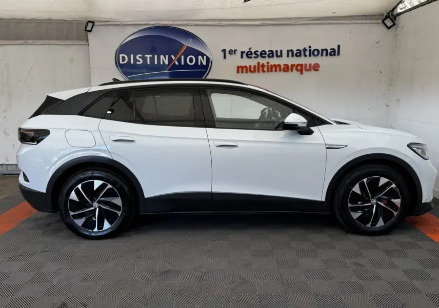 Vue de profil côté gauche d'un Volkswagen ID.4 blanc avec toit noir et jantes noires à motifs argentés.