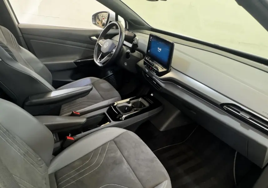 Vue intérieure côté conducteur du Volkswagen ID.4 blanc, avec tableau de bord épuré et écran tactile central.