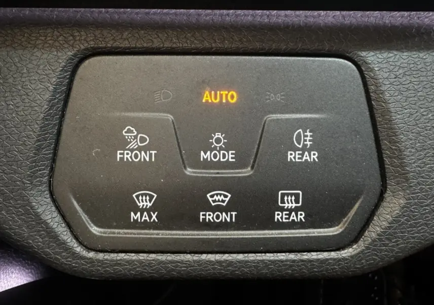 Gros plan sur le panneau de commande noir avec éclairage orange AUTO dans un Volkswagen ID.4 blanc.
