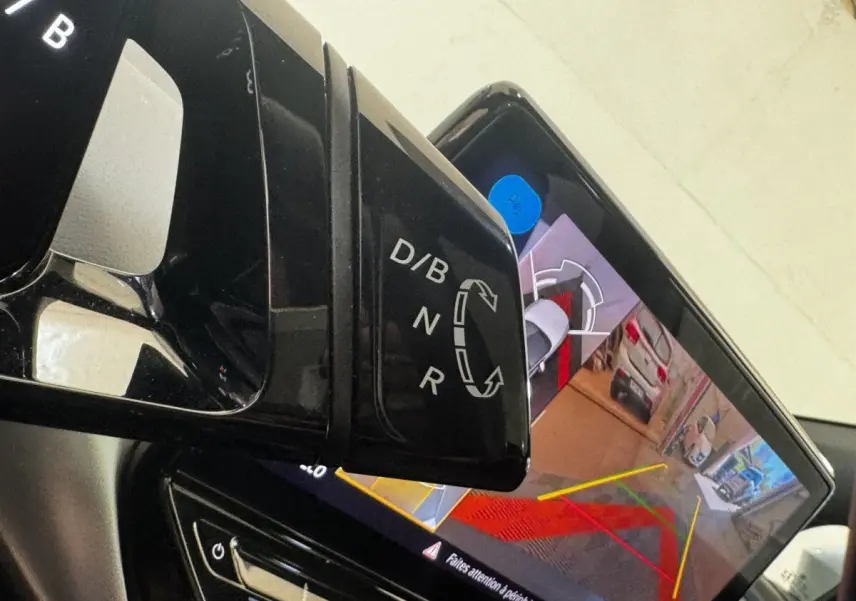 Gros plan sur le levier de vitesses noir et l'écran tactile affichant la caméra de recul dans un Volkswagen ID.4 blanc.