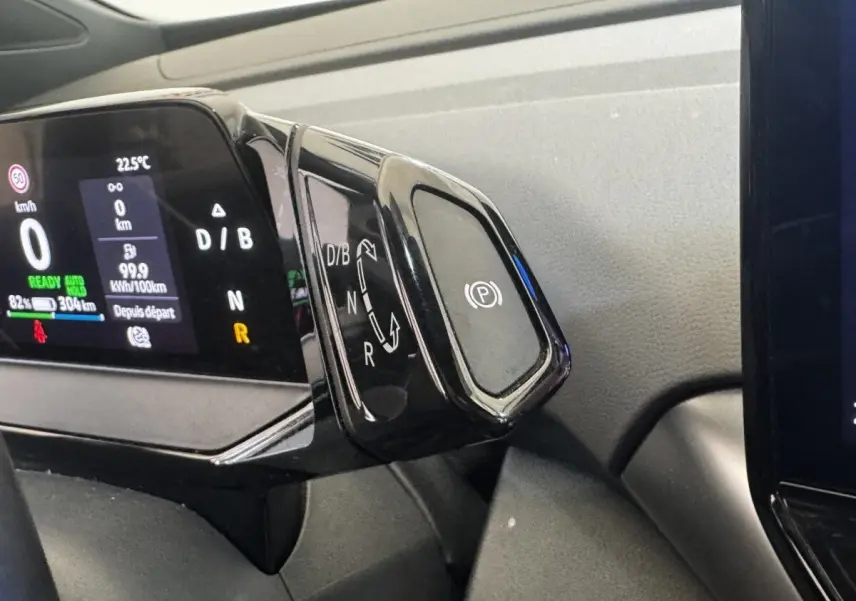 Gros plan sur la commande de boîte automatique noire et l’écran digital du tableau de bord du Volkswagen ID.4 blanc.