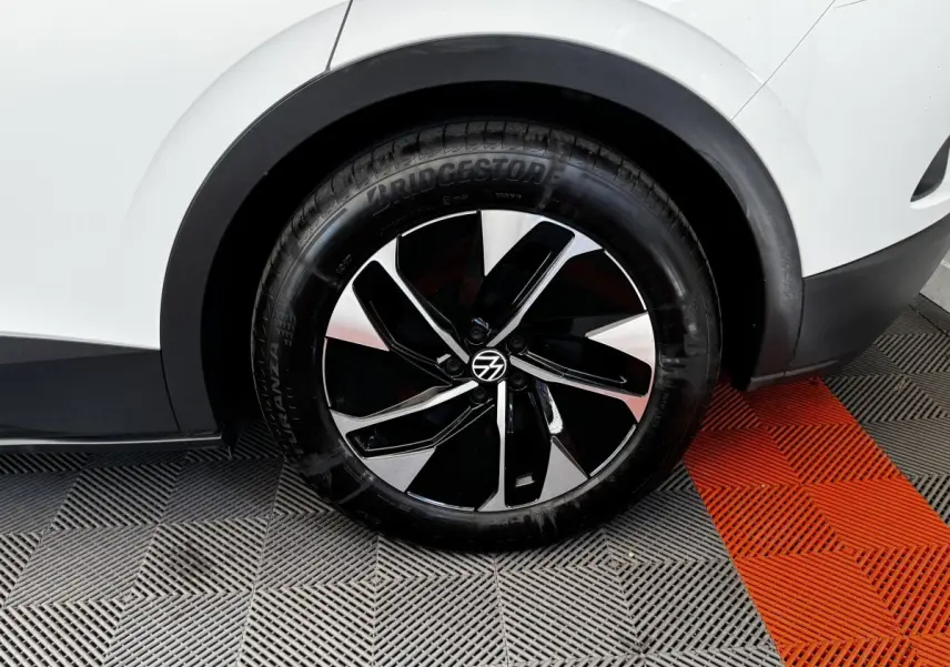 Gros plan sur la roue arrière droite noire et argentée du Volkswagen ID.4 blanc, avec partie de la carrosserie visible.