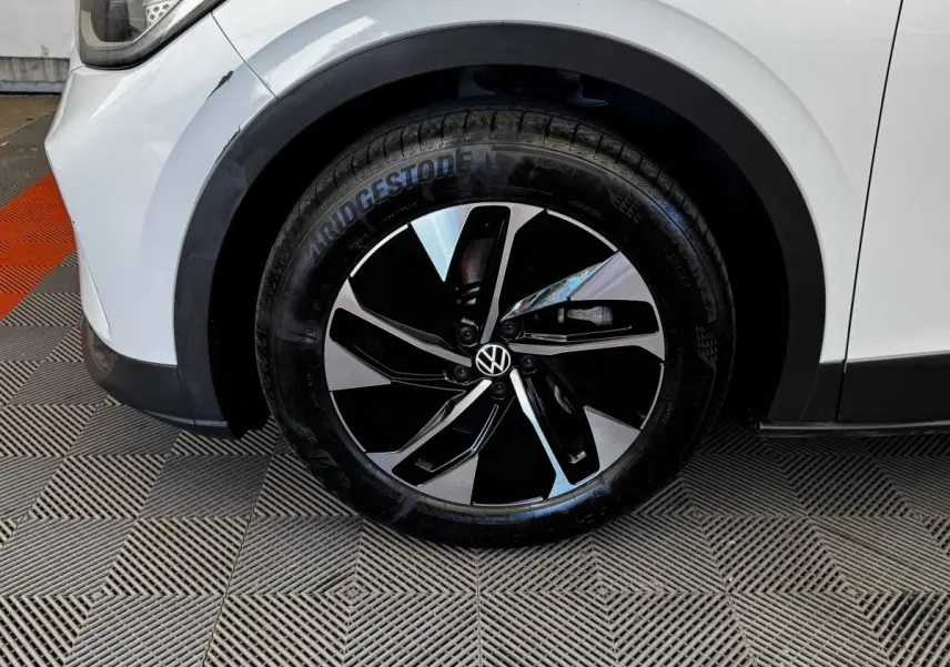 Gros plan sur la roue avant gauche blanche d’un Volkswagen ID.4 avec jante noire et argentée au design moderne.