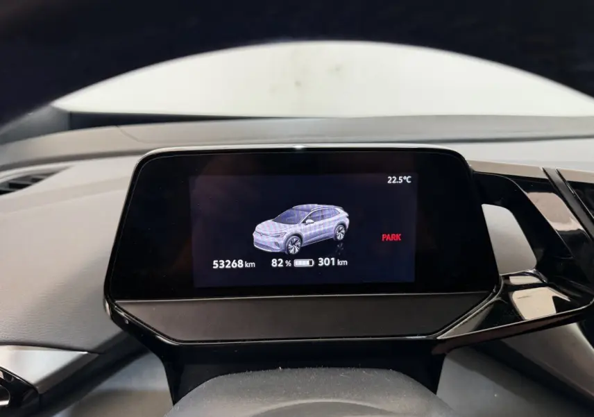 Écran numérique du tableau de bord montrant une Volkswagen ID.4 blanche en vue latérale, avec autonomie et température.