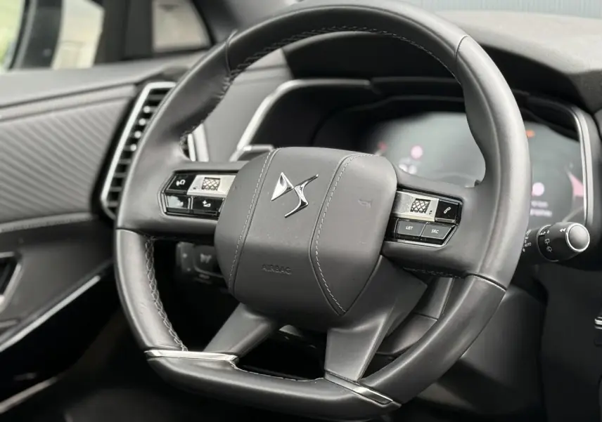 Gros plan sur le volant en cuir noir du DS7 2025, avec commandes intégrées et logo DS au centre.