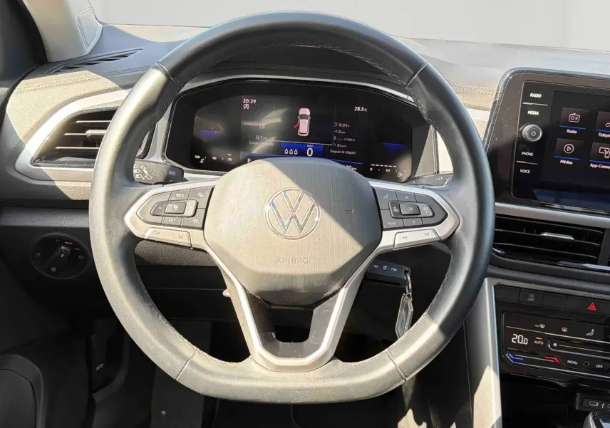 Vue intérieure centrée sur le volant cuir multifonctions du Volkswagen T-Roc 2025 avec tableau de bord digital et écran tactile.