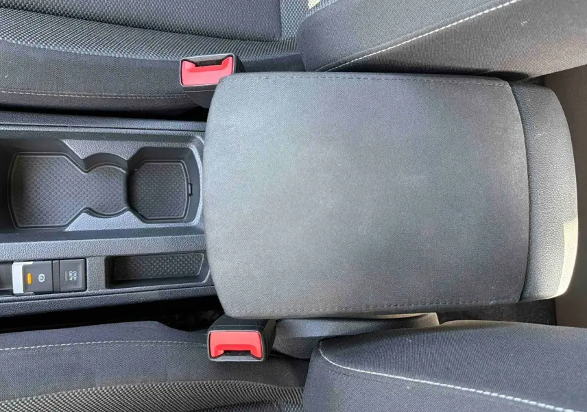 Vue plongeante sur l'accoudoir central noir et les sièges en tissu gris du Volkswagen T-Roc 2025.