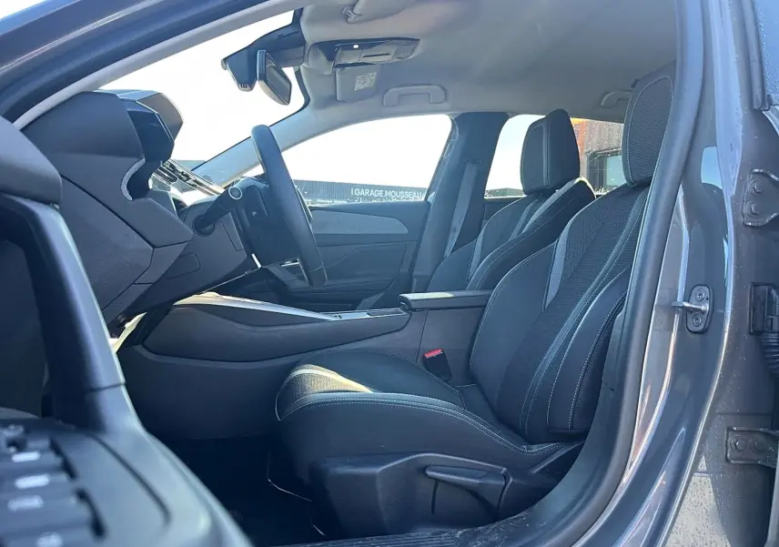Vue intérieure côté conducteur de la Peugeot 308 gris selenium, montrant les sièges avant et le volant multifonction.