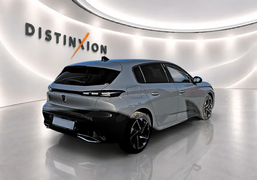 Peugeot 308 gris selenium vue 3/4 arrière droit en intérieur, vitres arrière surteintées et jantes alu noires.