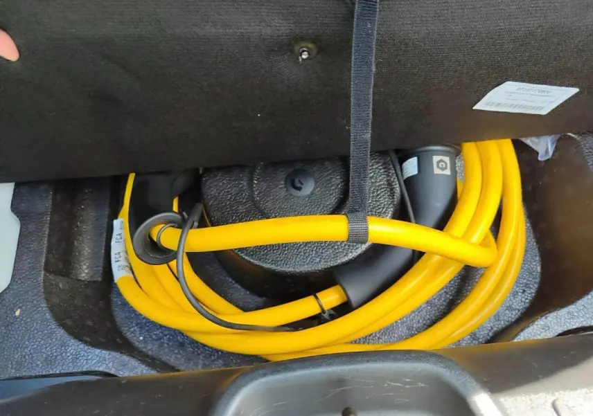 Gros plan sur le câble de recharge jaune rangé dans le coffre de la FIAT 500 électrique blanche, version 2024.