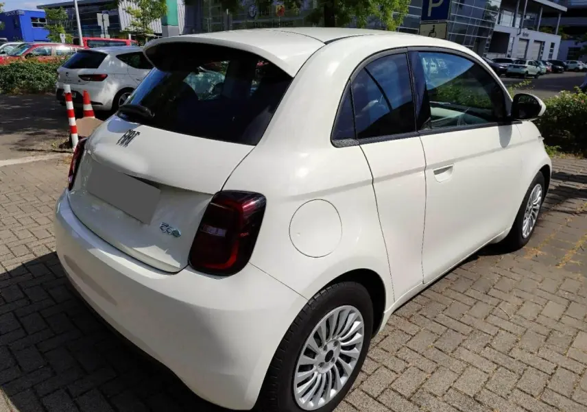Fiat 500 électrique blanche vue 3/4 arrière droit, avec feux arrière foncés et jantes multibranches.