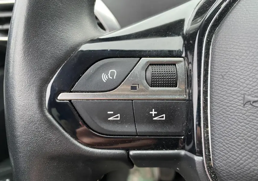 Gros plan sur les commandes de volume et de reconnaissance vocale du volant d'un Peugeot 3008 gris platinium.