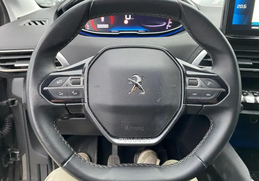 Volant compact en cuir noir du Peugeot 3008 2021 avec logo lion et tableau de bord numérique visible en arrière-plan.