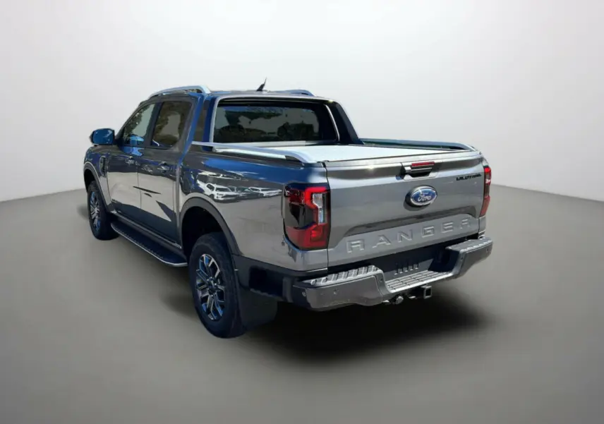 Ford Ranger 3.0 V6 240 Wildtrak Plus gris carbone vu en 3/4 arrière droit avec benne couverte et logo distinctif.