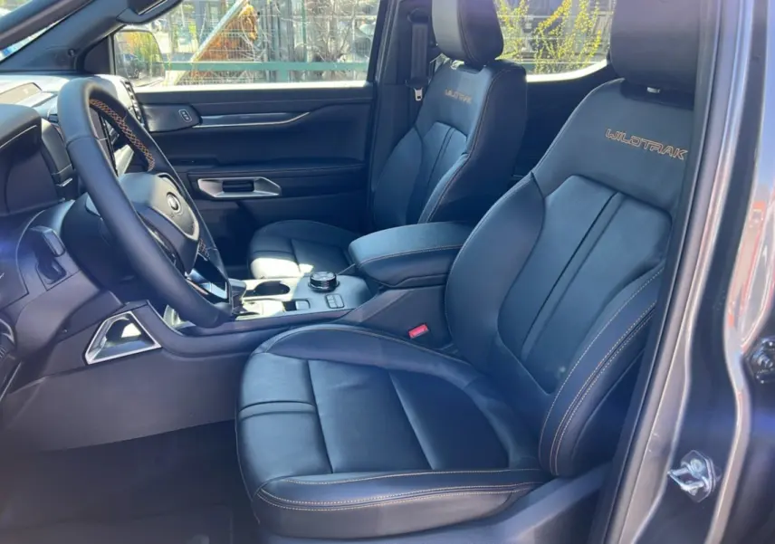 Intérieur du Ford Ranger 2025 gris carbone, vue côté conducteur sur les sièges en cuir Wildtrak avec surpiqûres orange.