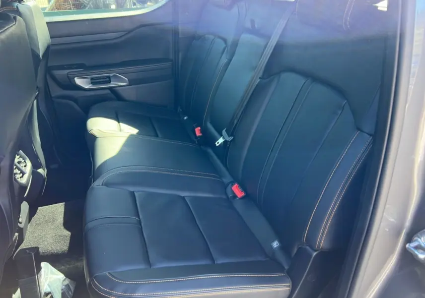 Vue intérieure côté droit des sièges arrière en cuir noir avec surpiqûres contrastantes du Ford Ranger 2025 gris carbone Wildtrak Plus.