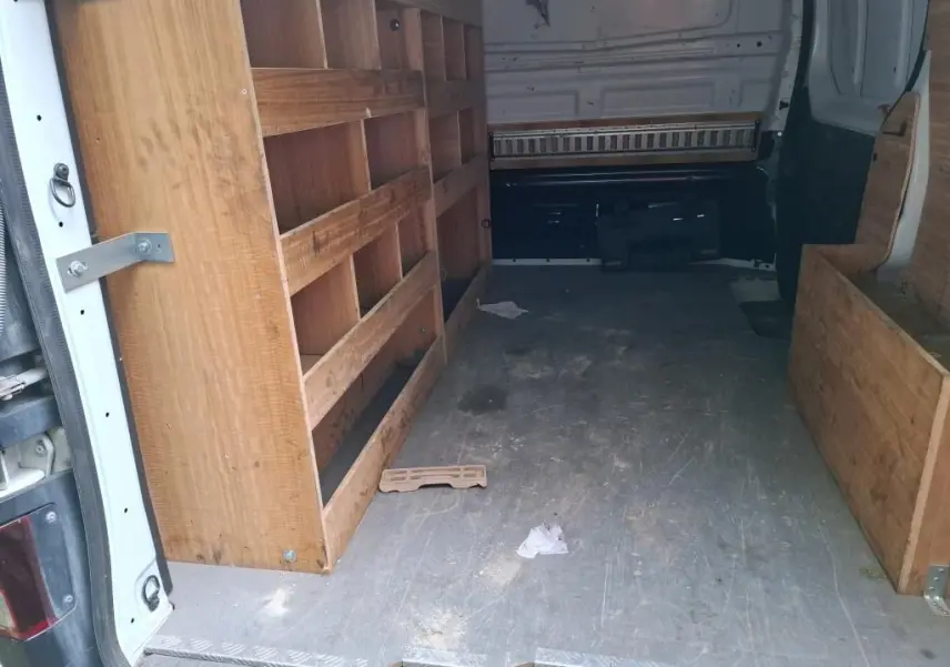 Intérieur du fourgon blanc Renault Trafic L1H1 2021 vu de l'arrière, avec aménagements en bois sur les côtés.