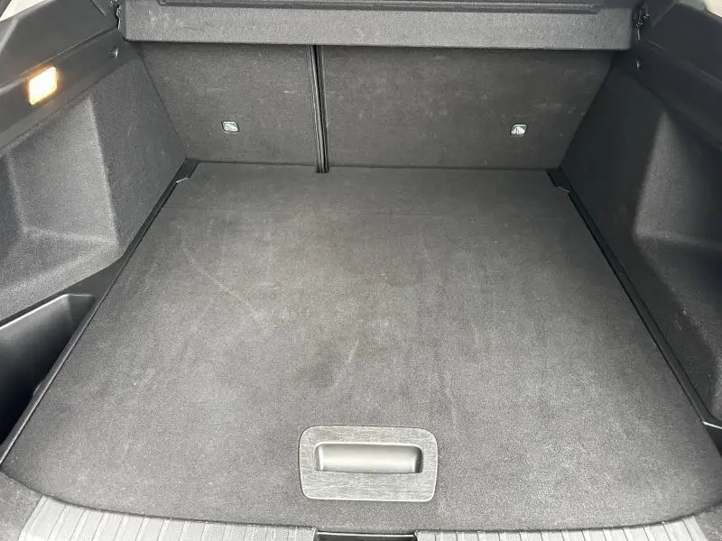 Vue plongeante sur le coffre spacieux et propre du Renault Arkana 2025, revêtement noir et éclairage latéral allumé.