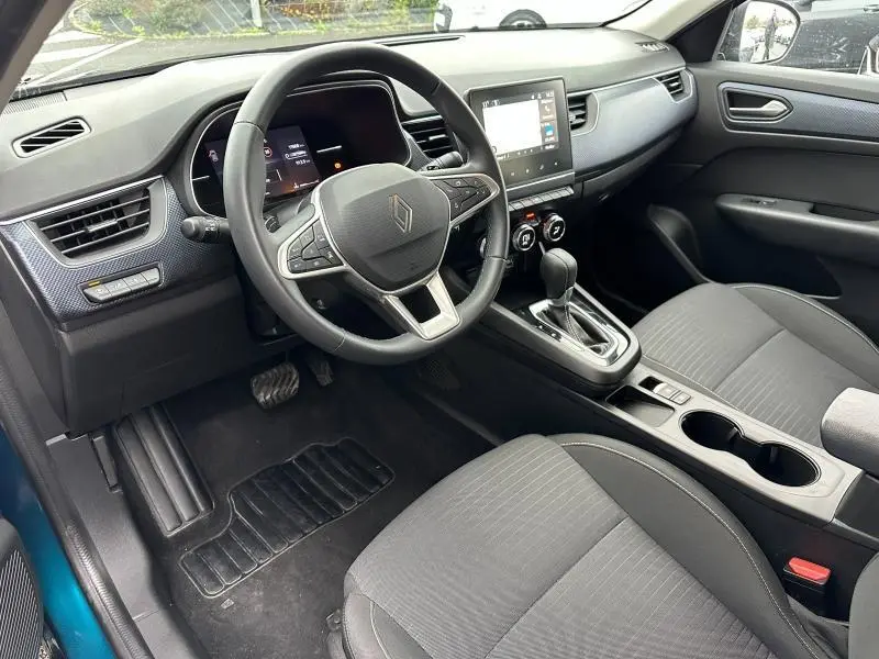 Intérieur du Renault Arkana 2025 vu côté conducteur, tableau de bord moderne avec écran tactile et volant multifonction.