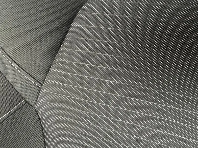 Détail du tissu gris anthracite avec surpiqûres blanches du siège avant du Renault Arkana 2025.