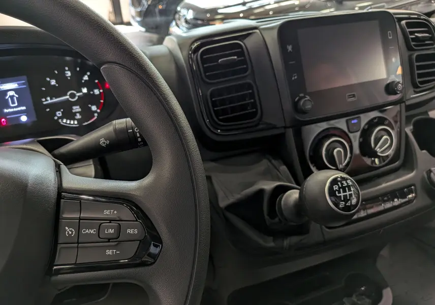 Vue intérieure rapprochée du tableau de bord et levier de vitesse manuel du Fiat Ducato Fourgon blanc, avec commandes au volant visibles.
