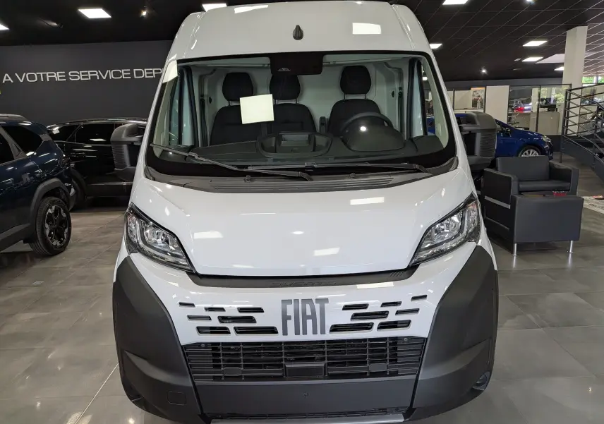 Vue frontale d'un FIAT Ducato Fourgon blanc 2026 en showroom, avec calandre noire et logo FIAT bien visible.