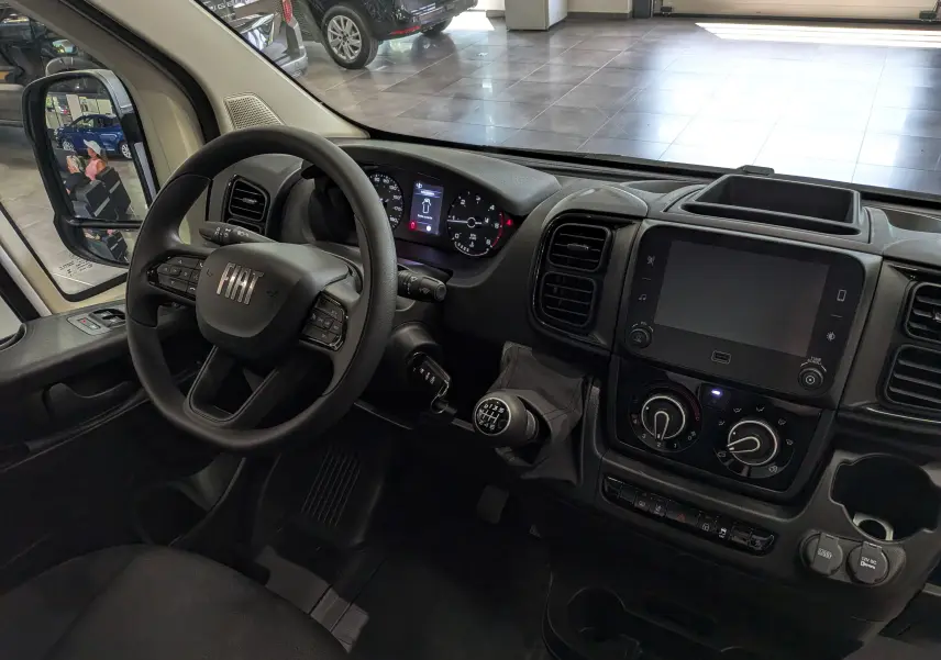Vue intérieure côté conducteur du Fiat Ducato Fourgon blanc 2026, volant multifonction et tableau de bord avec écran tactile.