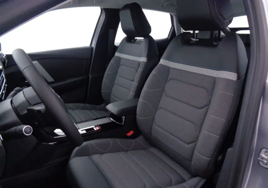 Intérieur de la Citroën C4 2023, vue côté conducteur, sièges tissu gris avec surpiqûres bleues et accoudoir central.