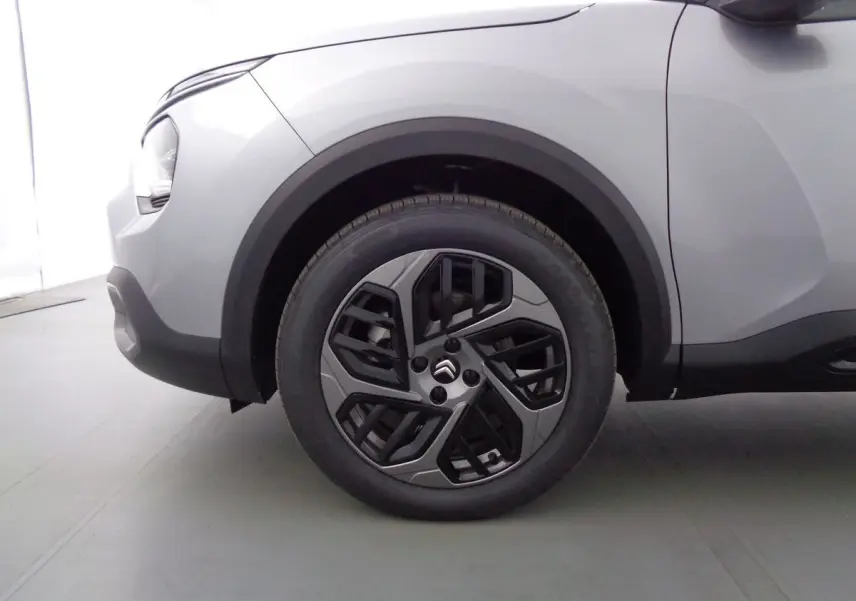 Gros plan sur la roue avant gauche d'une Citroën C4 gris Artense métal avec jante alliage bicolore au design moderne.
