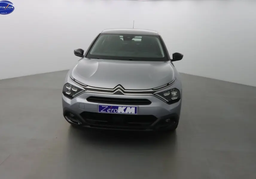 Citroën C4 gris Artense métal vue de face dans un studio, mettant en valeur ses phares LED et sa calandre distinctive.