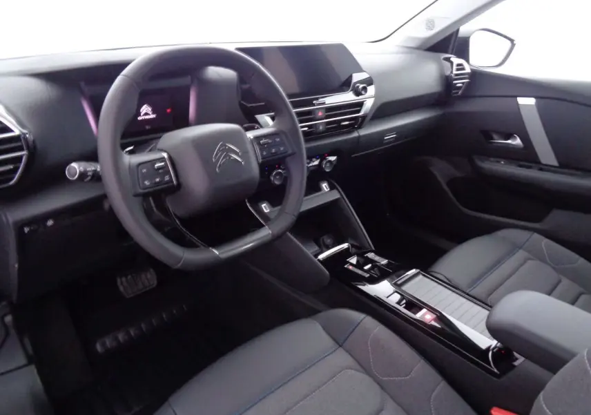 Vue intérieure côté conducteur de la Citroën C4 2023 avec tableau de bord noir et volant multifonction.