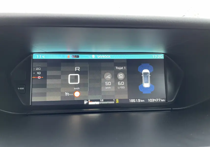 Affichage numérique du tableau de bord du Citroën Grand C4 Picasso gris, montrant vitesse, consommation et capteurs de proximité.