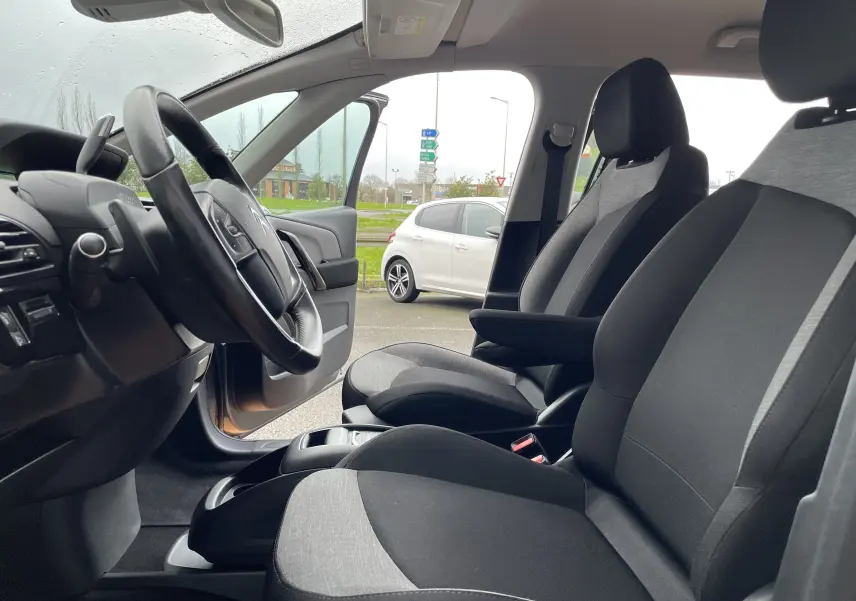 Intérieur avant du Citroën Grand C4 Picasso gris 2018, sièges tissu bicolore et volant multifonction visible côté conducteur.