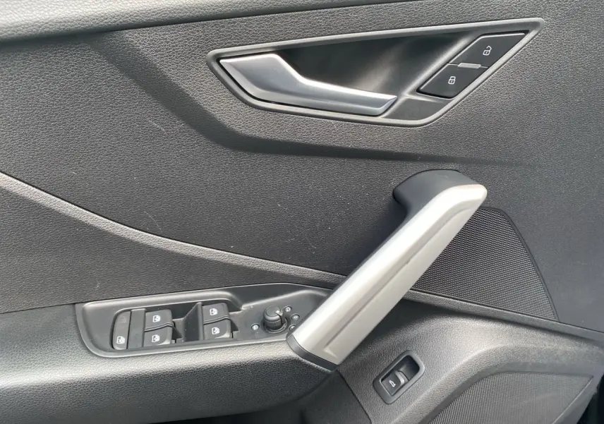 Détail de la porte côté conducteur de l'Audi Q2 2023 noir Mito avec commandes de vitres et serrure intégrée.